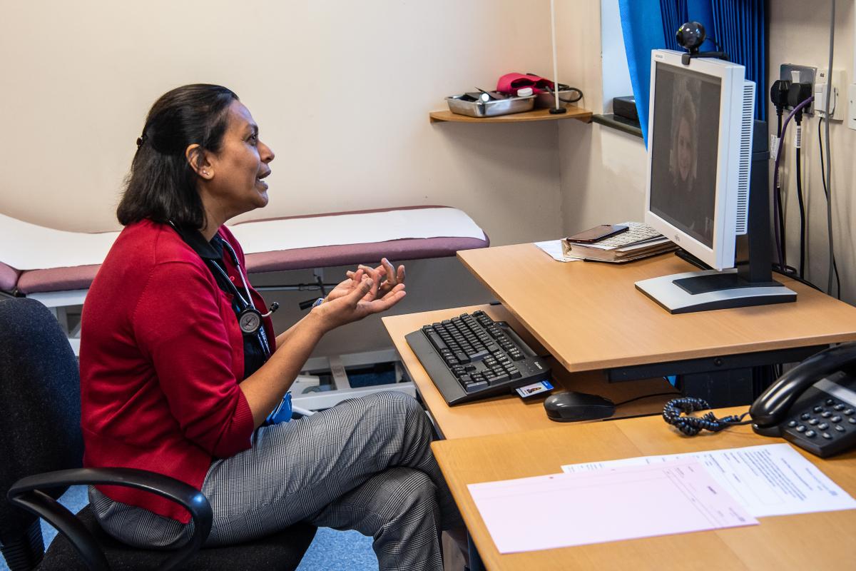 Clinician sitting in front of a screen having a video consultation with a patient